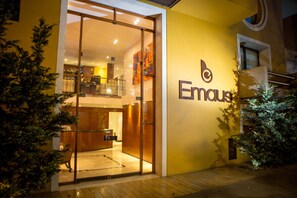 A modern building with a glass entrance, a visible reception area, and a logo on the wall. - Hotel Emaus Bogotá (Bogotá)