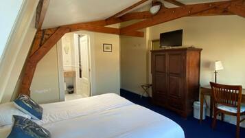 Een slaapkamer met een bed, houten balken, een bureau en een stoel.