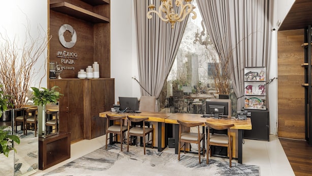 Een moderne kantoorruimte met een houten bureau, meerdere stoelen en een groot raam met gordijnen.