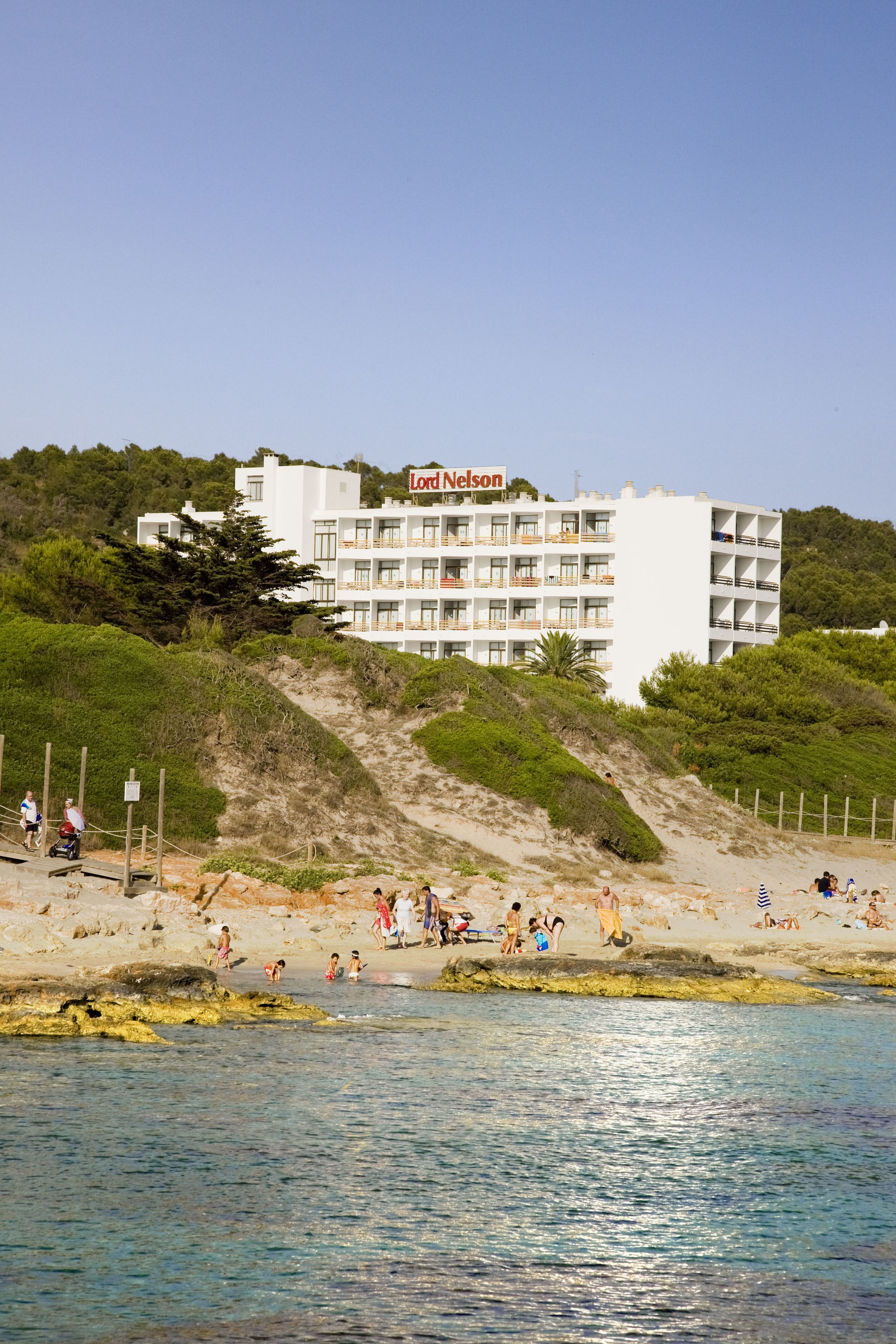 A hotel with multiple balconies and a beach in the foreground.