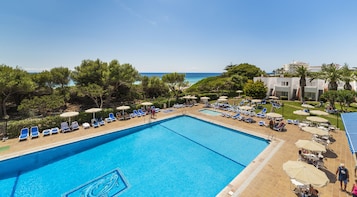 Una piscina al aire libre, sombrillas, sillones reclinables de piscina
