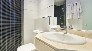 A modern bathroom with a large sink, toilet, and a glass shower enclosure.