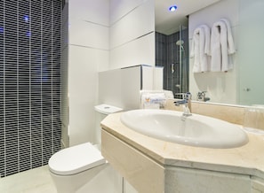 Un baño moderno con lavamanos grande, inodoro y cabina de ducha de vidrio.