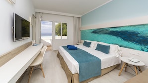 Habitación de hotel moderna con una cama grande, un escritorio, televisión y vistas al mar a través de la ventana.