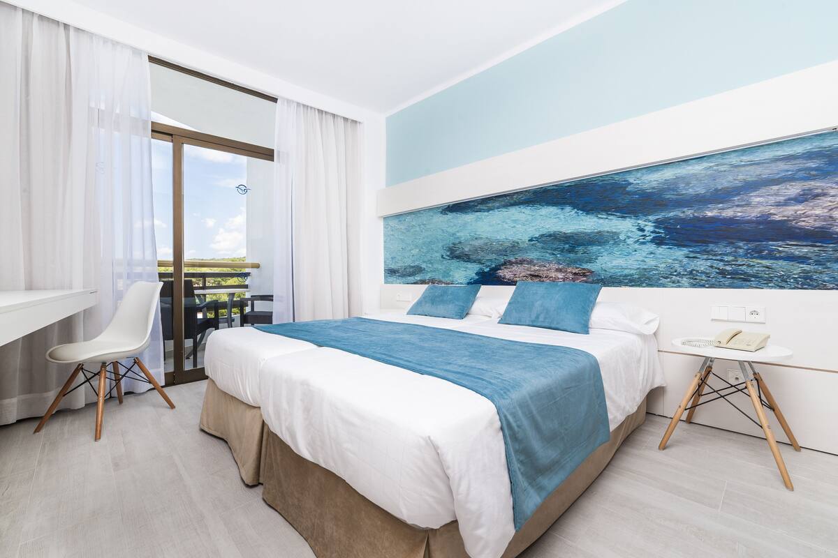 Habitación de hotel moderna con una cama grande, un escritorio y vistas al exterior.