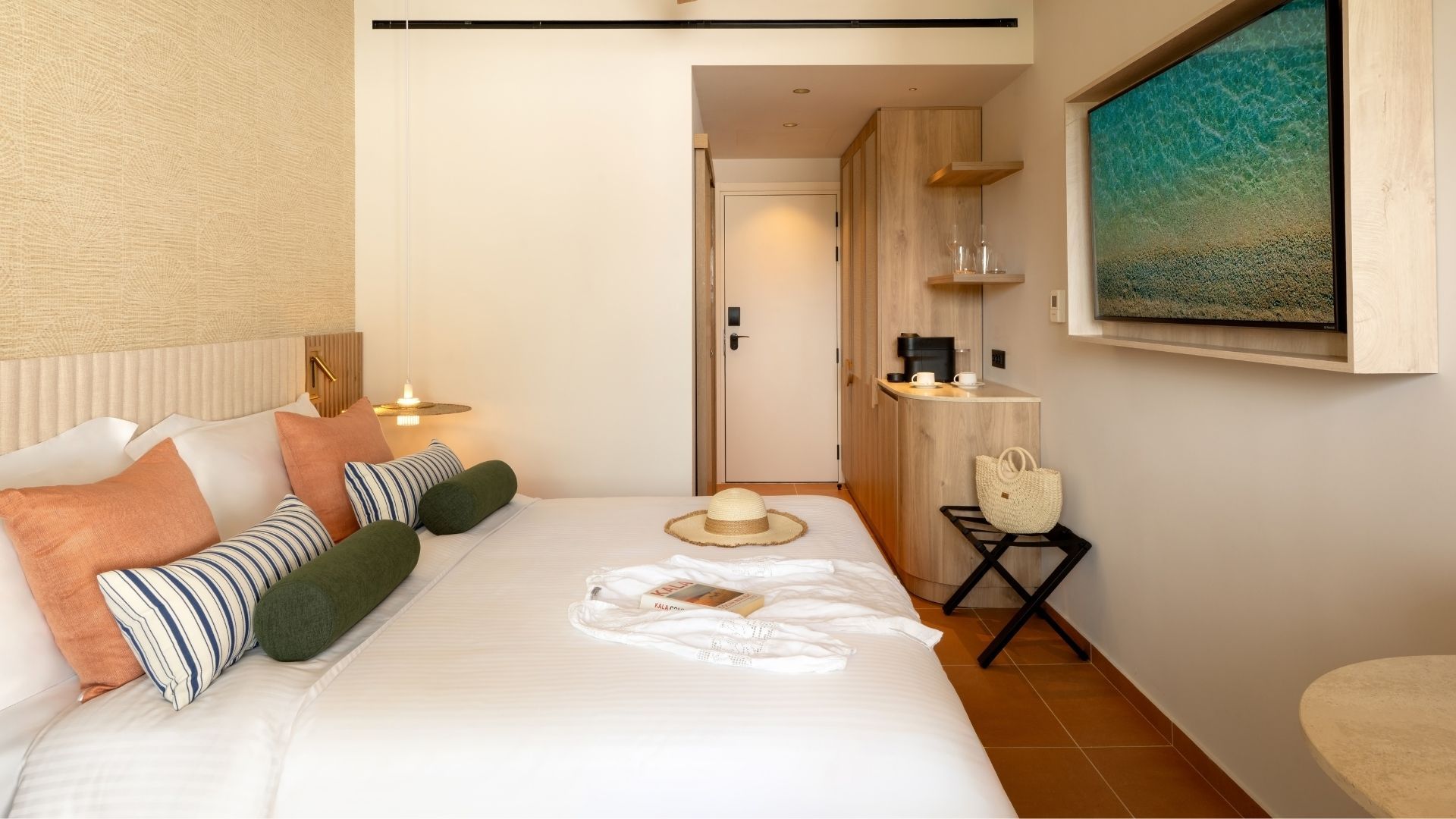 A hotel room with a bed, bedside table, and a painting on the wall.