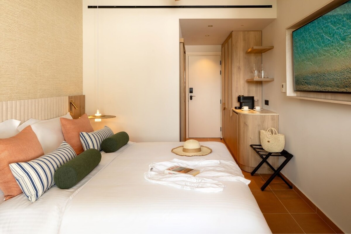 A hotel room with a bed, bedside table, and a painting on the wall.