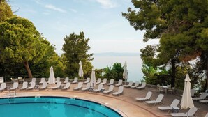 A poolside area with lounge chairs and umbrellas, overlooking a body of water. - Canvas by Mitsis Alexander the Great (Kassandra)