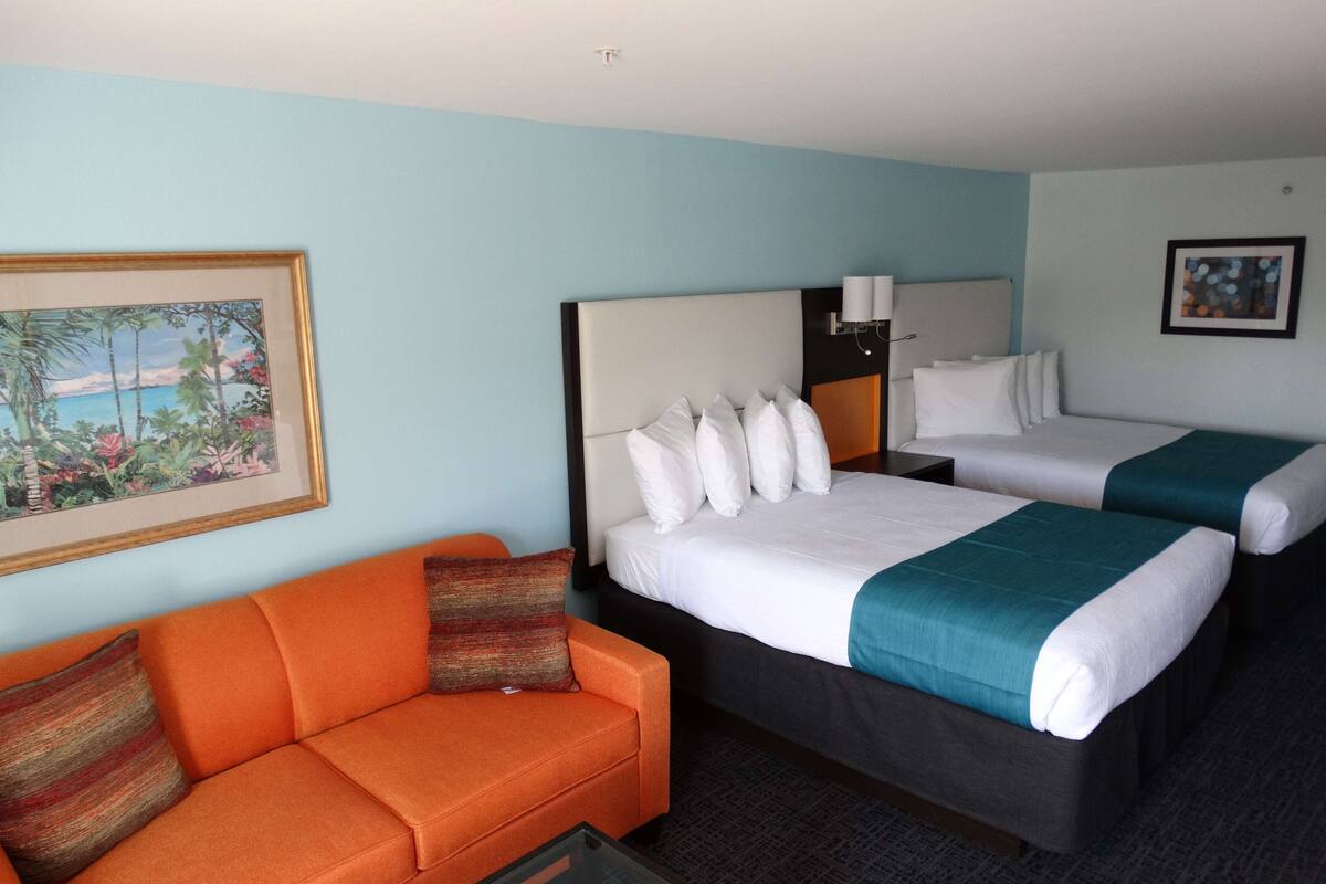 Ein Hotelzimmer mit zwei Betten, einem Schlafsofa und einem Bild an der Wand.