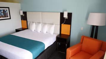 A hotel room with a large bed, two bedside tables, a nightstand, a chair, and a lamp.