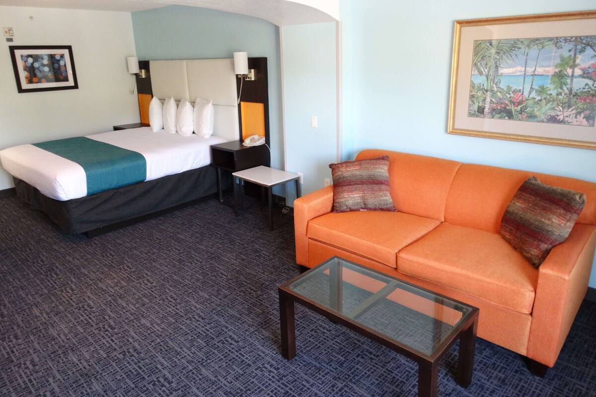 Ein Hotelzimmer mit einem Bett, einem Sofa, einem kleinen Tisch und einem Bild an der Wand.
