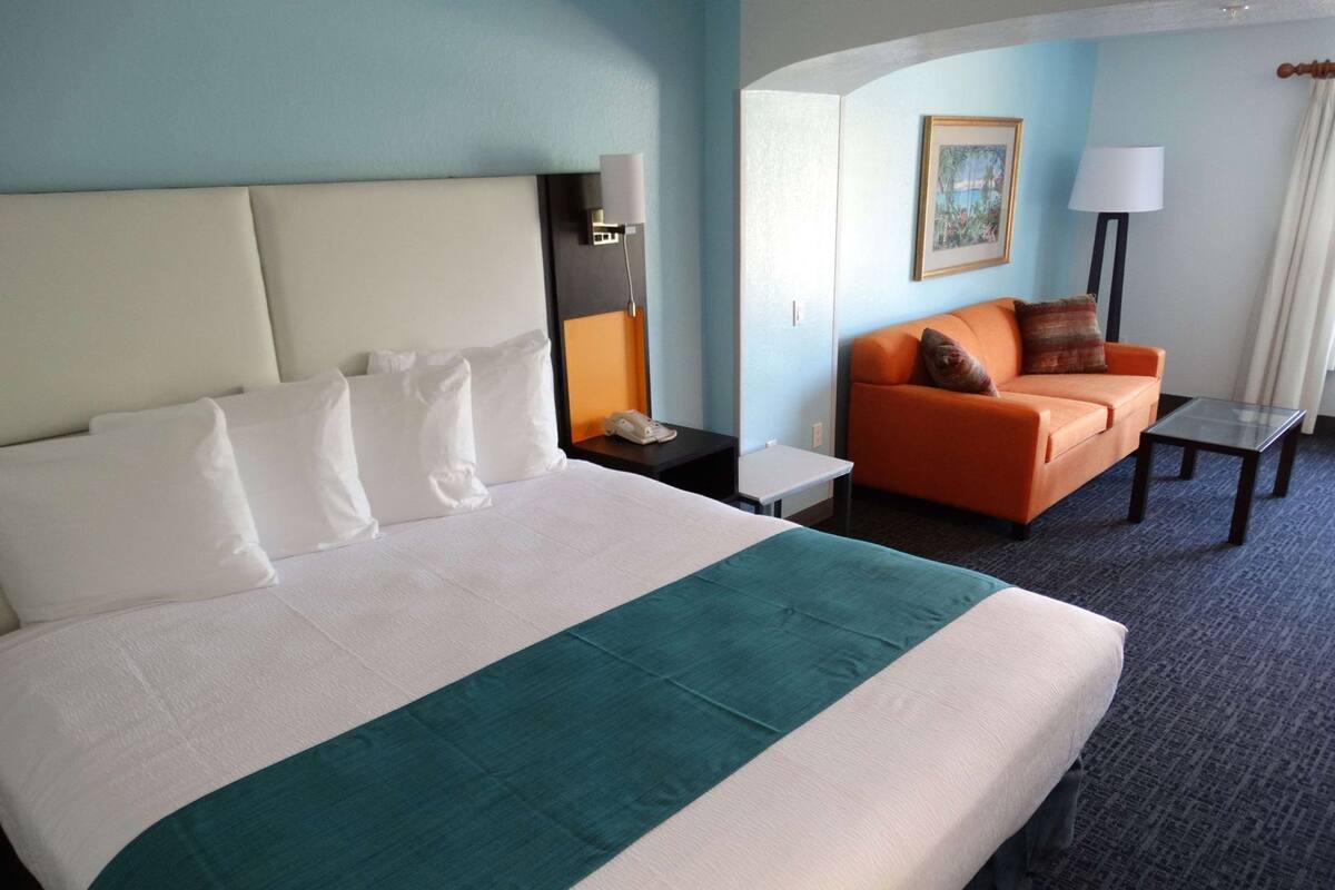Ein Hotelzimmer mit einem großen Bett, einer Couch, einem kleinen Tisch, einer Lampe und einem Gemälde an der Wand.