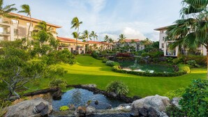 A resort with multiple buildings, a well-maintained lawn, a pond, and palm trees. - Marriott's Waiohai Beach Club (Koloa)