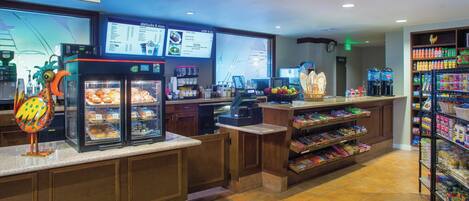 A grab&go counter with a menu display, refrigerated display cases, and a beverage dispenser.