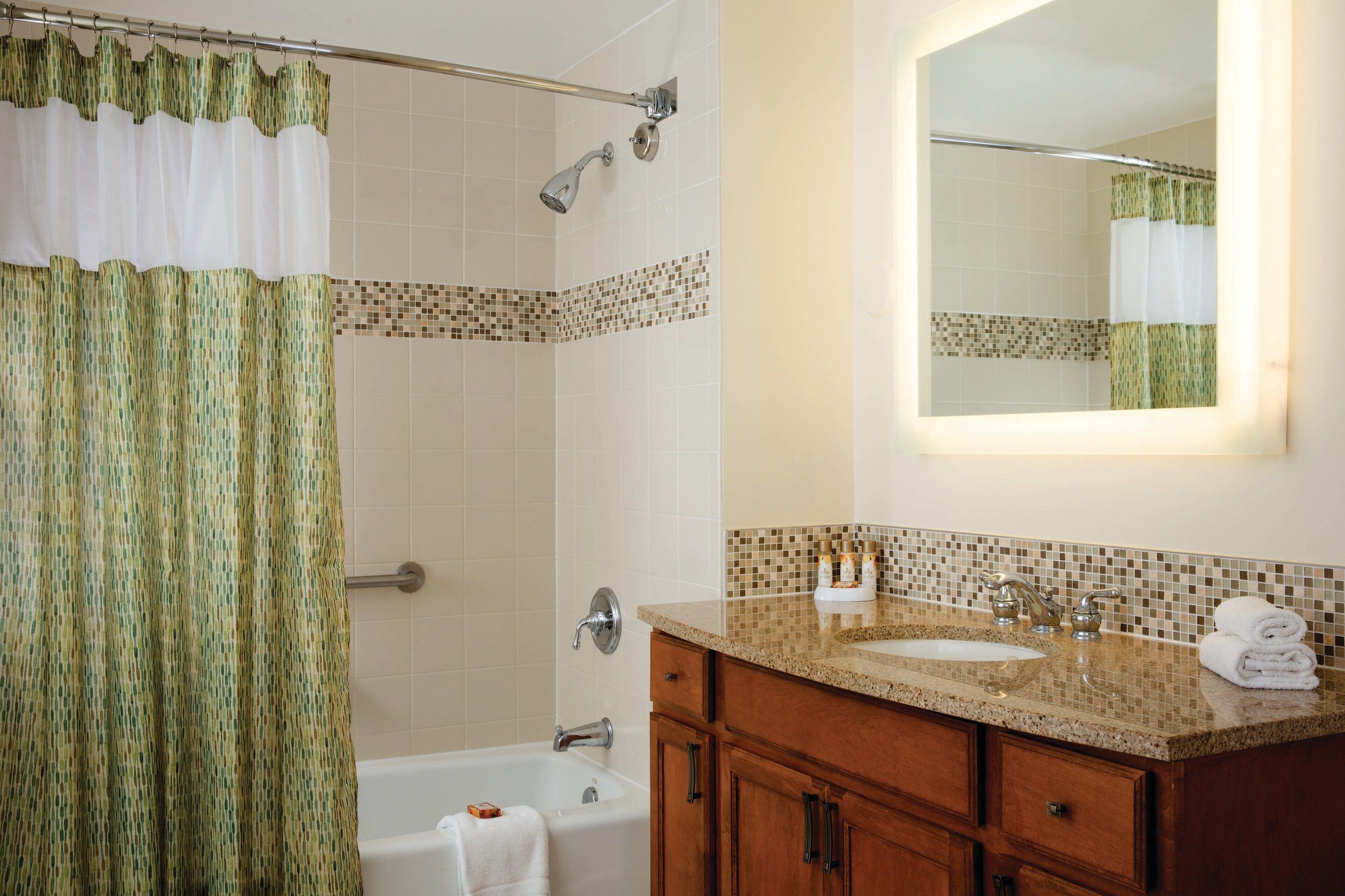 A bathroom with a shower, a bathtub, a sink, and a vanity with cabinets.