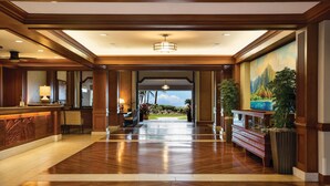A spacious lobby with a wooden floor, a reception desk, a large painting of a mountain landscape, and a view of the outdoors. - Marriott's Waiohai Beach Club (Koloa)