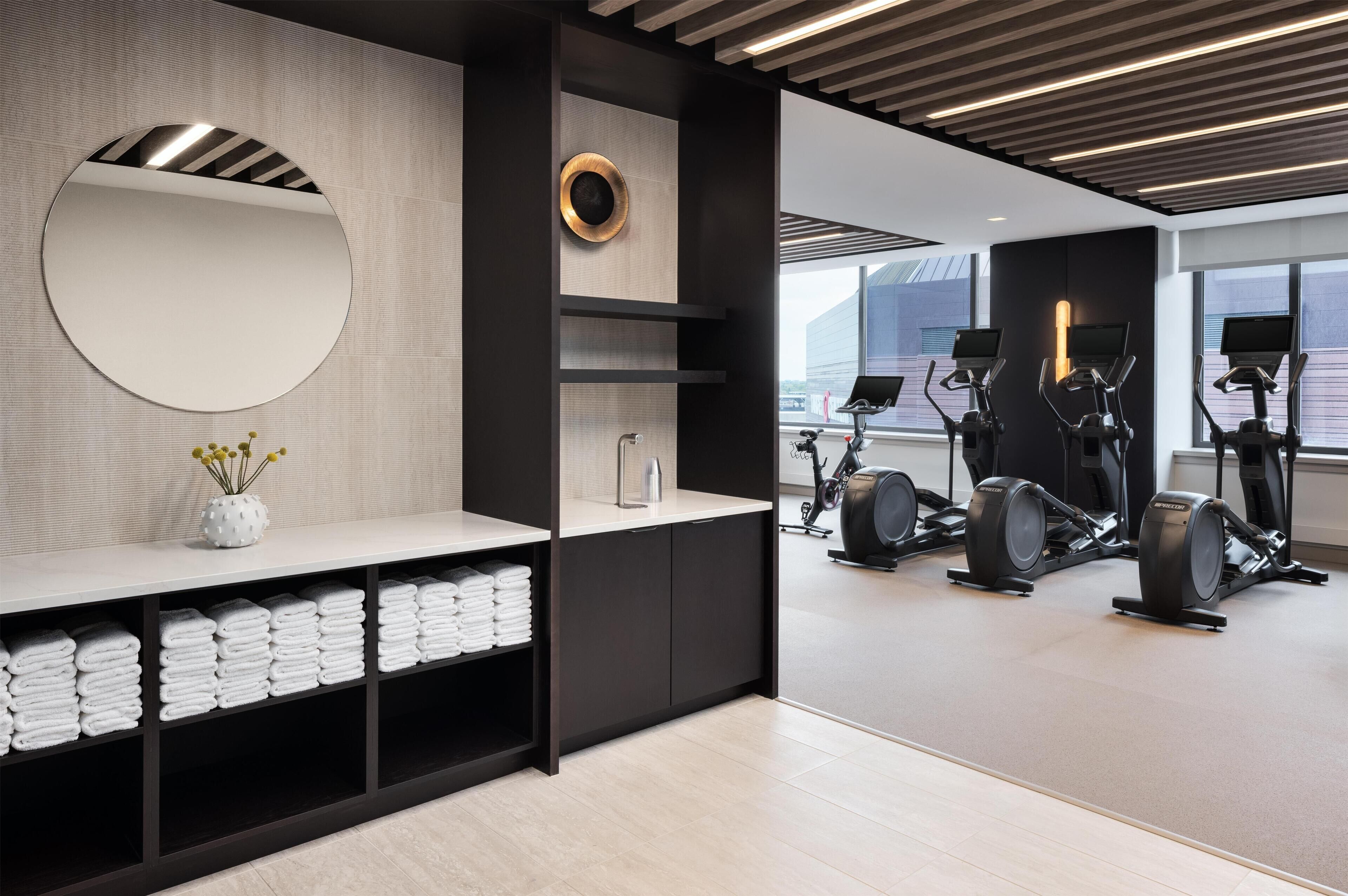 A modern gym with exercise equipment, a mirror, and neatly folded towels.