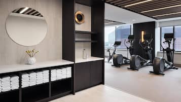 A modern gym with exercise equipment, a mirror, and neatly folded towels.