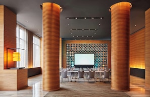 A modern conference room with wooden columns, a large screen, and a patterned wall.