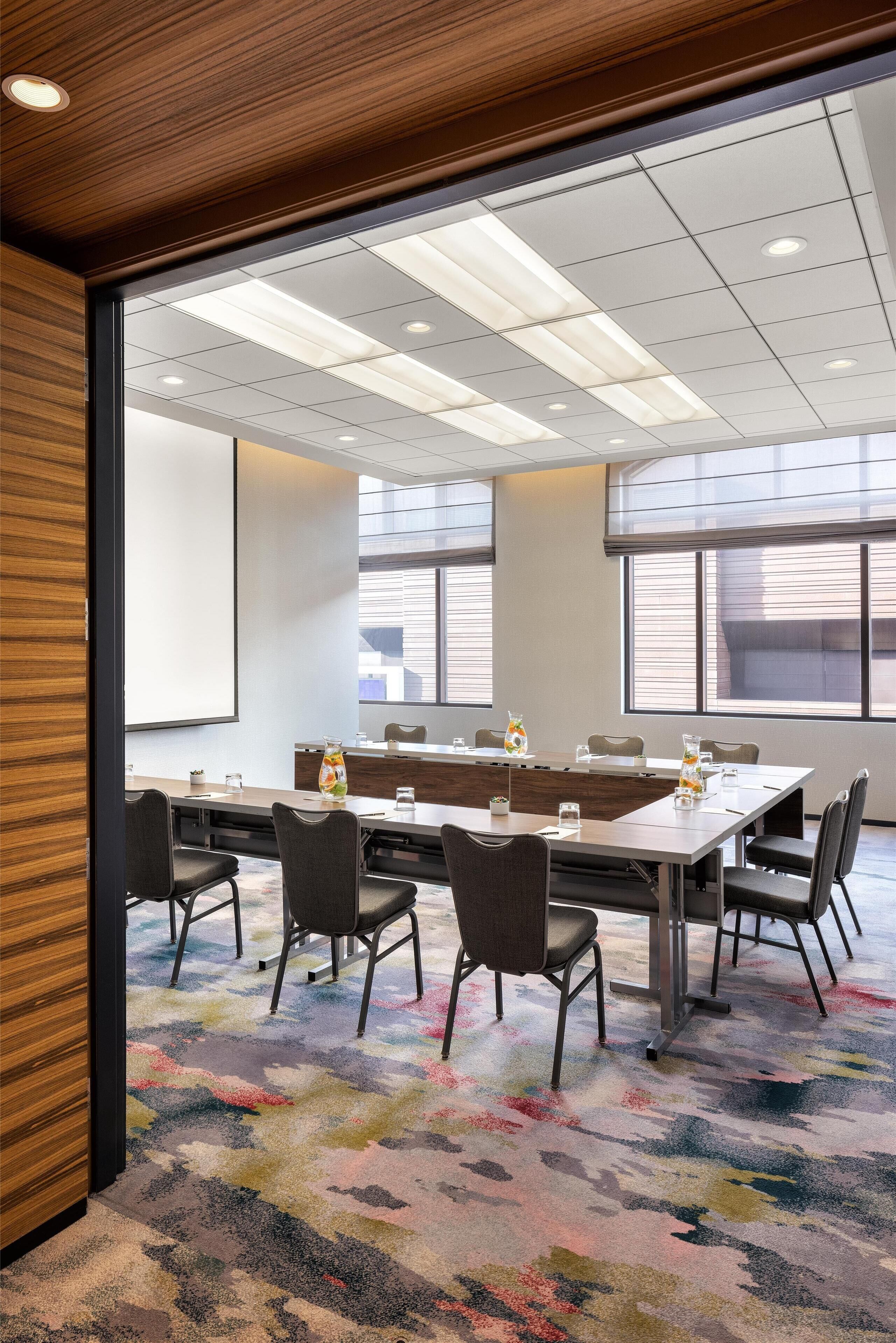 A conference room with a long table, chairs, and a projector screen.