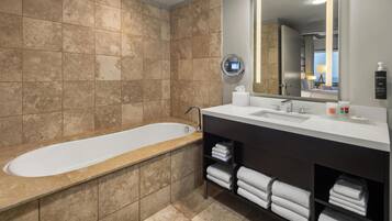 Un baño moderno con bañera, un espejo grande y tocador con toallas.