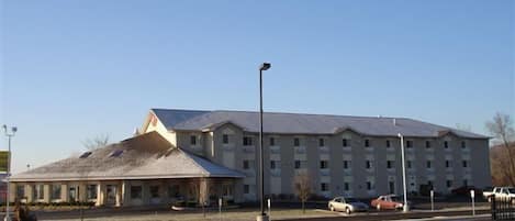 A multi-story building with a flat roof and a parking lot in front.