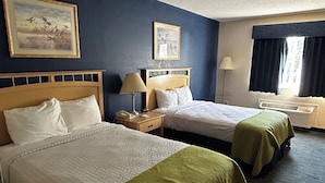 Habitación de hotel con dos camas, una mesita de noche con lámpara, una ventana con cortinas y un cuadro en la pared.