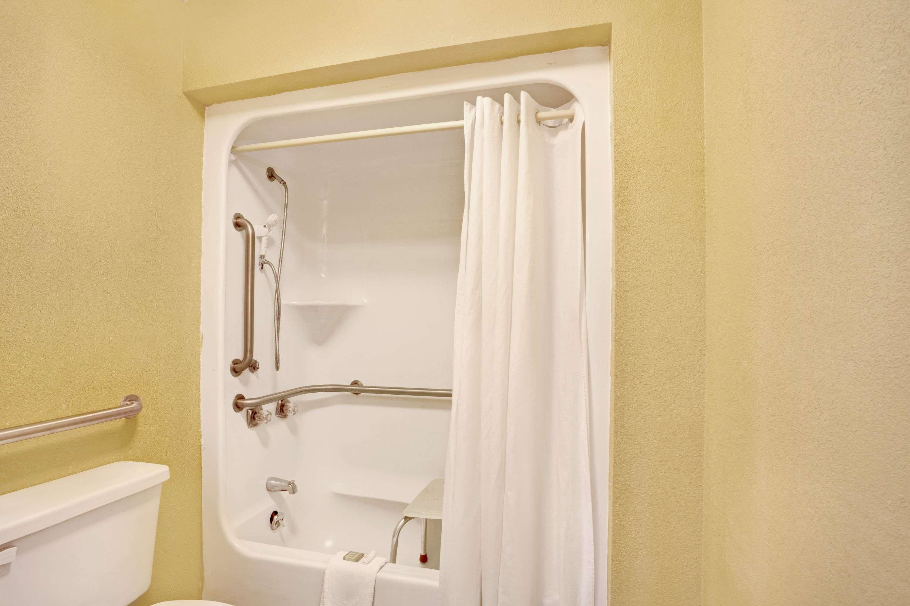 A bathroom with a bathtub, grab bars, and a toilet.