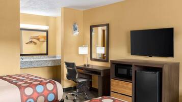 A hotel room with two beds, a desk, a chair, a television, and a refrigerator.