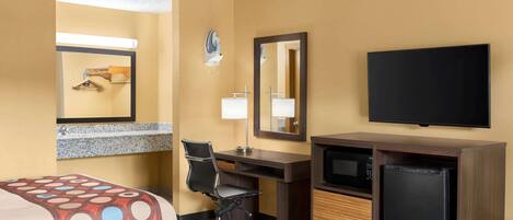 A hotel room with two beds, a desk, a chair, a television, and a refrigerator.
