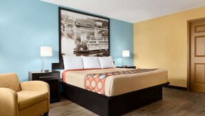 A hotel room with a large bed, two bedside tables, a chair, and a framed picture on the wall. - Super 8 by Wyndham Whites Creek/ Nashville NW Area (Whites Creek)