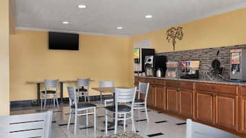 A modern kitchen with granite countertops, wooden cabinets, and a flat-screen TV mounted on the wall.