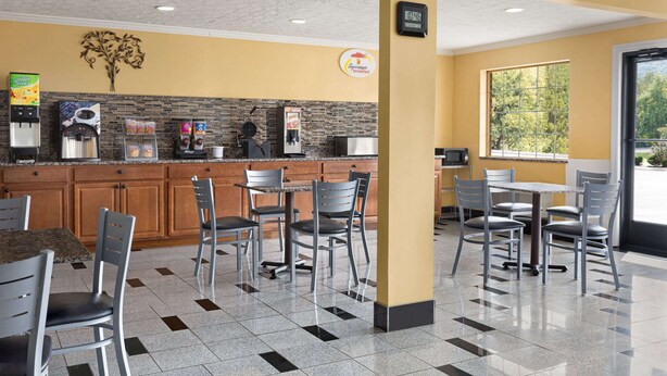 A breakfast area with a counter, seating, and a clock. - Super 8 by Wyndham Whites Creek/ Nashville NW Area (Whites Creek)