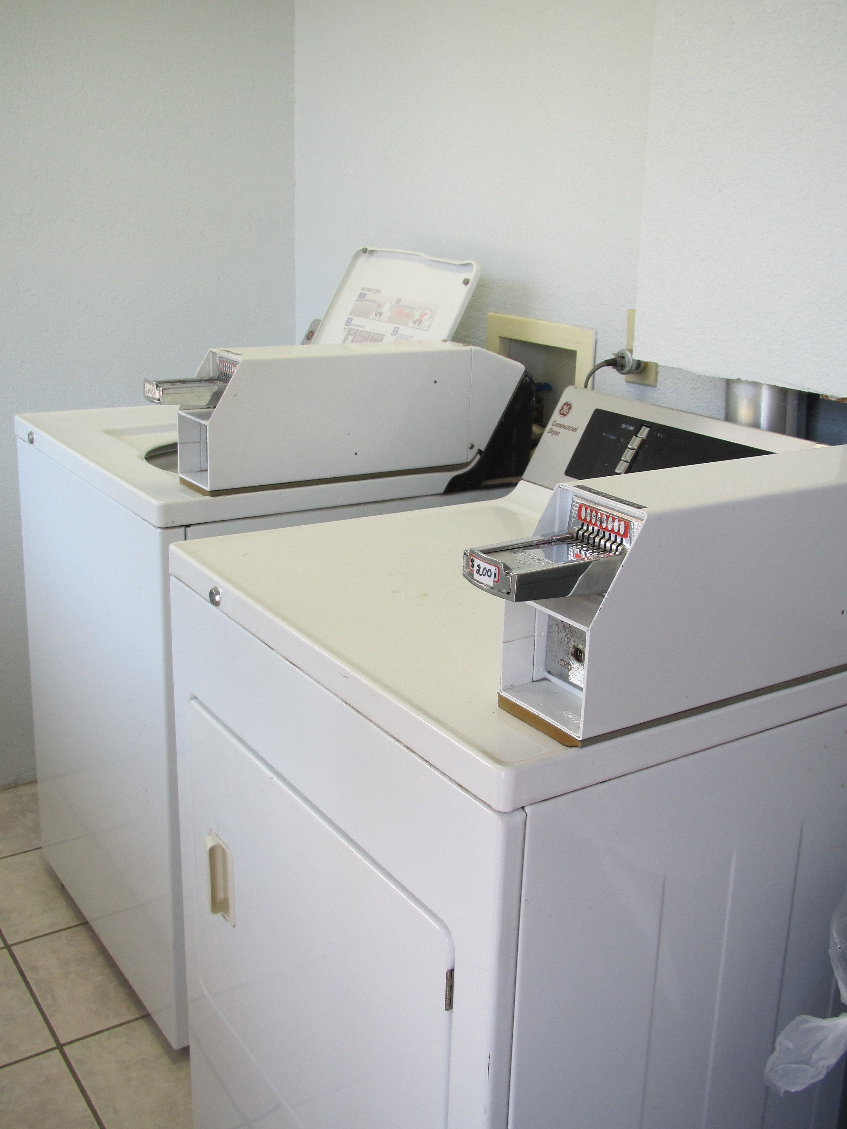 A laundry room with two white washing machines and a dryer.