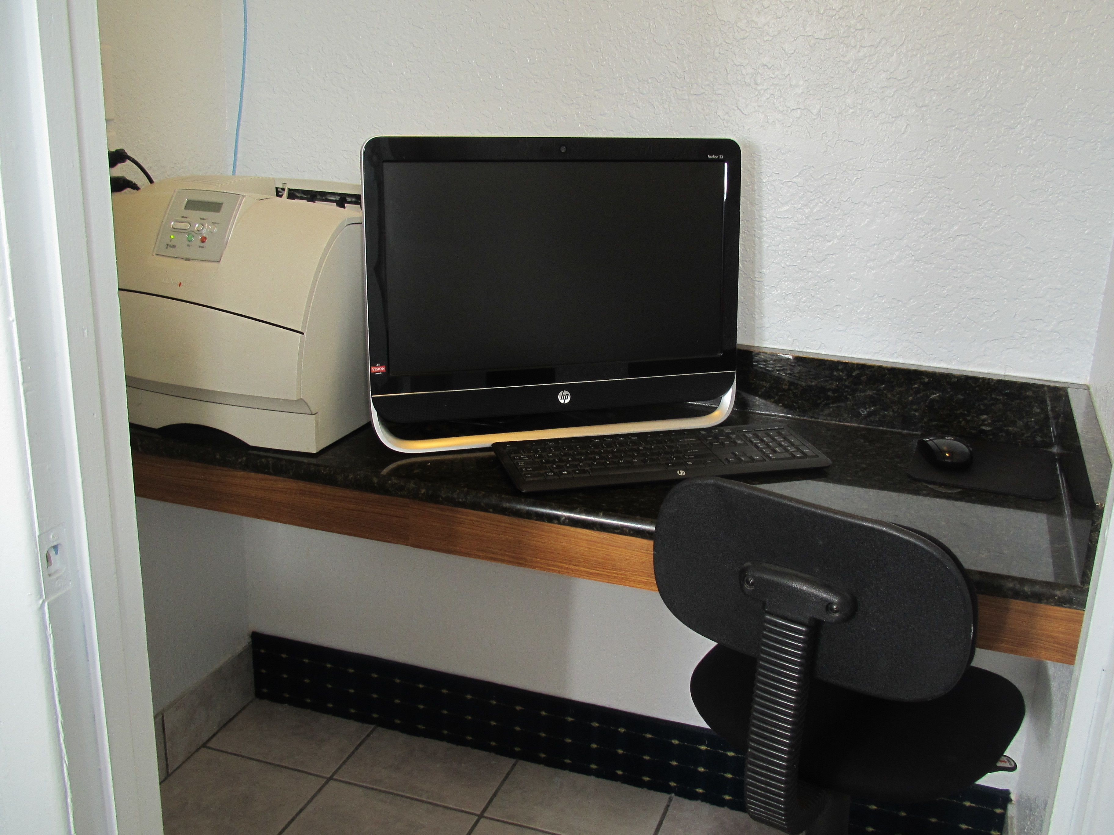 Un petit bureau équipé d’un ordinateur de bureau, d’une imprimante et d’un clavier, le tout posé sur un comptoir.