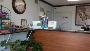A reception desk with a clock, a calendar, and various items like snacks and a plant.