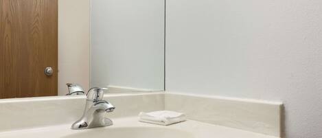 Un baño con un lavabo blanco, un espejo y una puerta de madera.