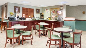 Un restaurant avec un comptoir, des chaises à coussins verts et une horloge au mur.