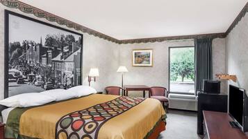 Habitación de hotel con una cama grande, un escritorio, una silla, un televisor y una ventana con cortinas.