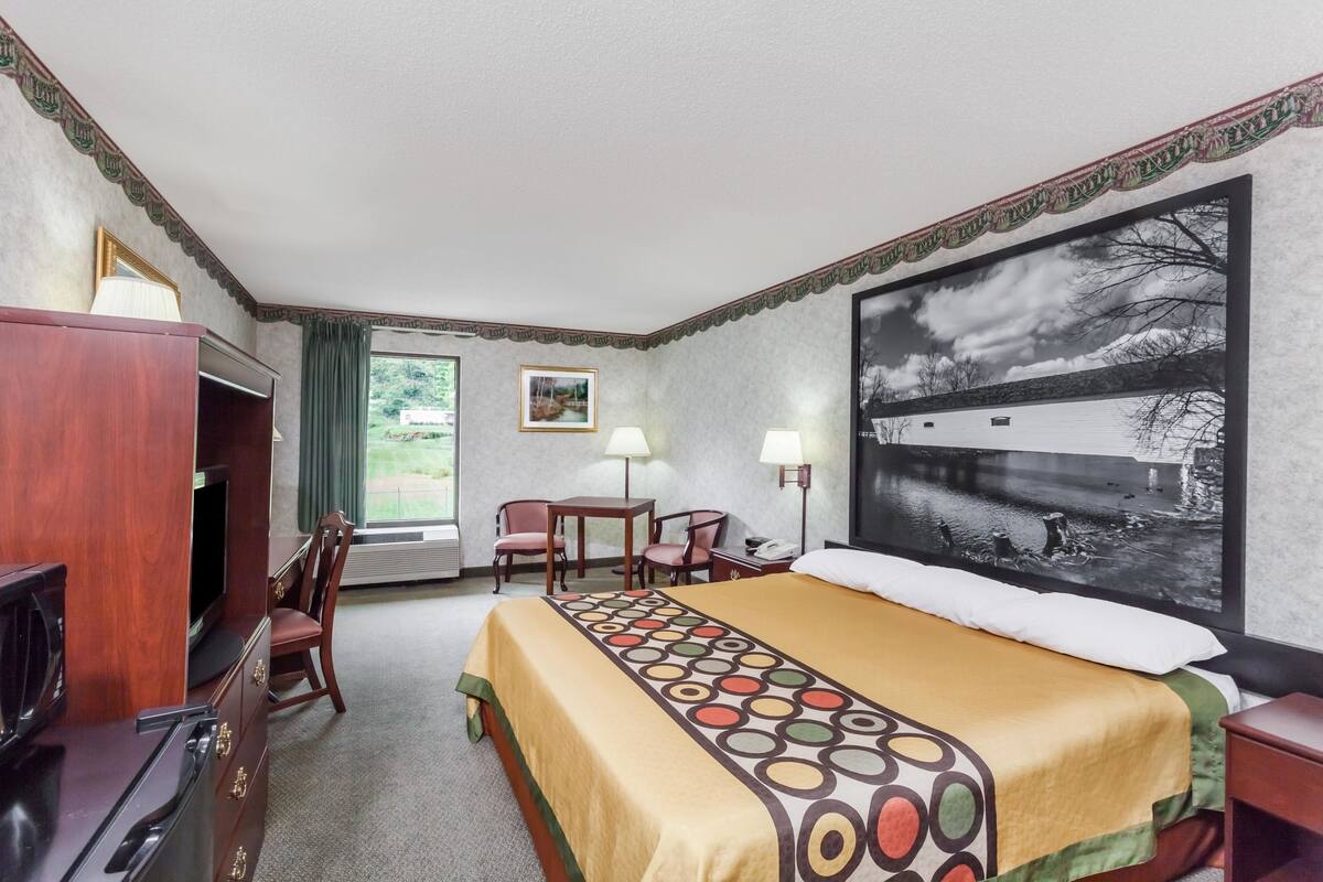 Une chambre d’hôtel équipée d’un lit, d’un bureau, d’une chaise, d’une télévision et d’une grande fenêtre.