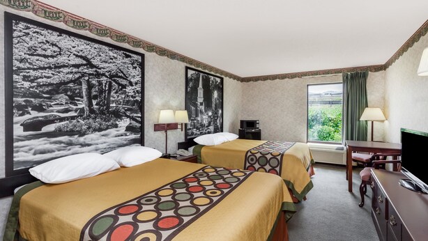 Une chambre d’hôtel avec deux lits, un bureau, une télévision et une grande fenêtre.