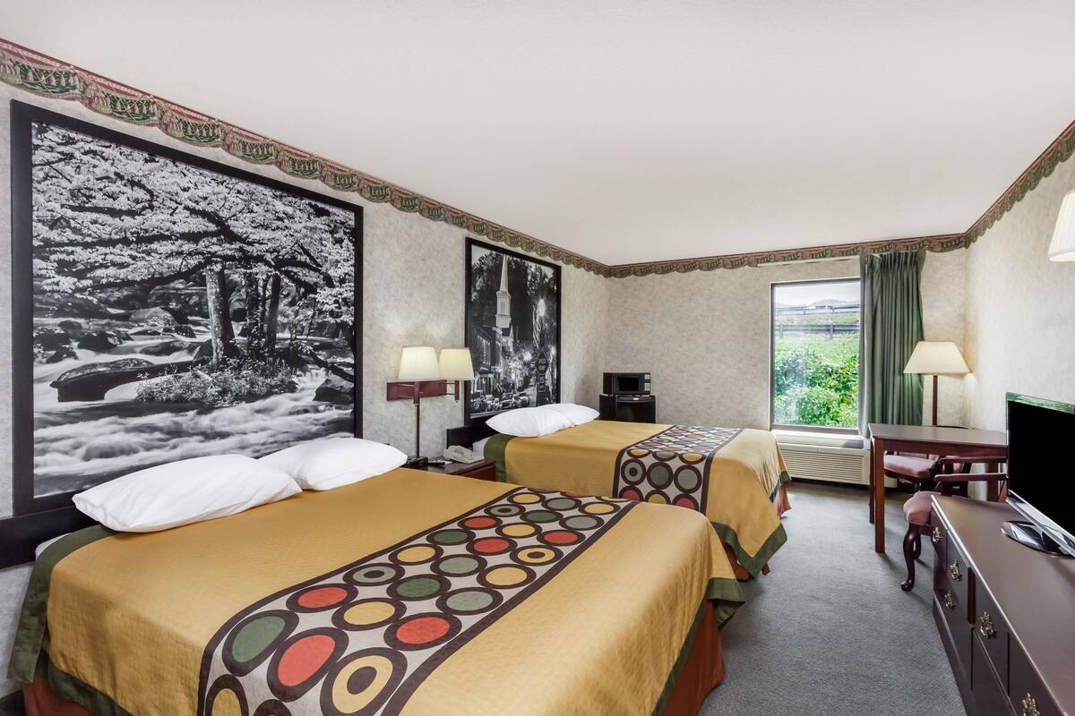 Une chambre d’hôtel avec deux lits, un bureau, une télévision et une grande fenêtre.