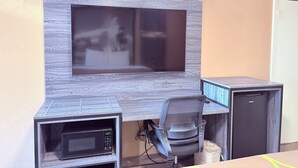 Een moderne kantoorruimte met een ingebouwde televisie, een bureau, een stoel en een kleine koelkast.