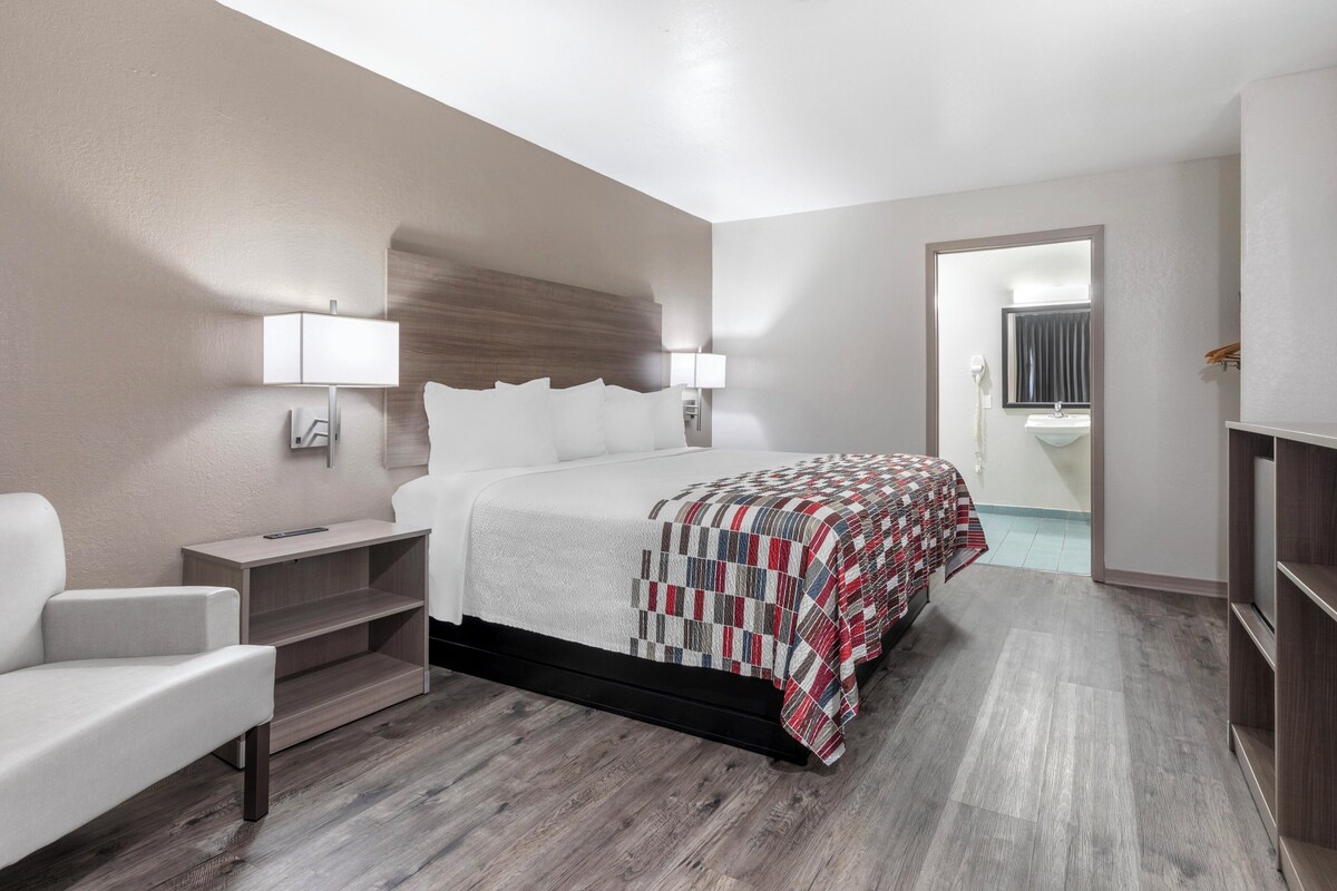 Una habitación de hotel moderna con una cama grande, una mesita de noche, una silla y un armario.