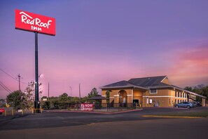 Un hotel Red Roof Inn con un letrero grande, un estacionamiento y un edificio con paneles solares.