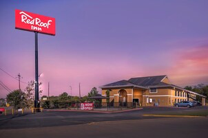 Un hotel Red Roof Inn con un letrero grande, un estacionamiento y un edificio con paneles solares.