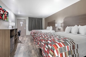 A hotel room with a large bed, a desk, and a television.