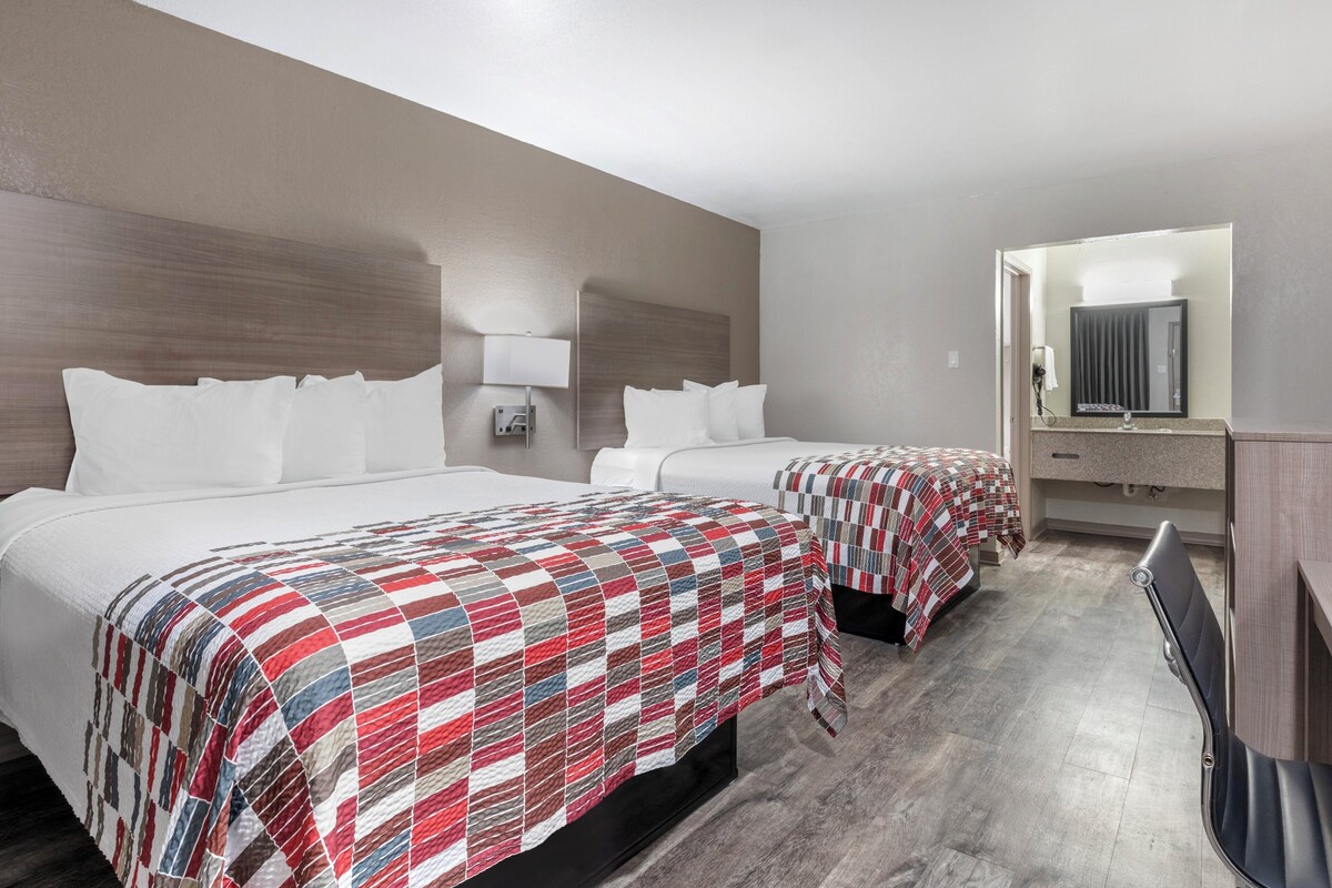 Una habitación de hotel con dos camas, un espejo grande y una mesita pequeña.
