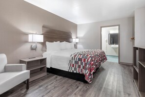 A hotel room with a bed, bedside tables, a chair, a wardrobe, and a bathroom visible through an open door. - Red Roof Inn Canton, TX (Canton)