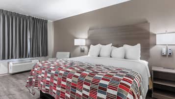 Une chambre d’hôtel avec un lit, une table de chevet, une lampe, un radiateur et une fenêtre avec des rideaux.